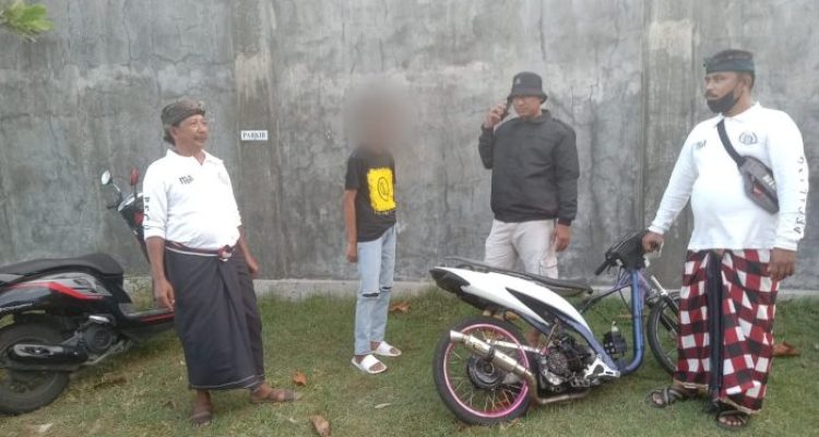 Ket poto: Salah satu pelaku trek-trekan diamankan petugas kepolisian bersama Pecalang setempat