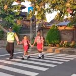 Ket poto: Bhabinkamtibmas II Kelurahan Baler Bale Agung bantu menyebrangkan anak-nak sekolah