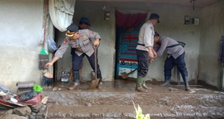 Ket poto: Petugas kepolisian bantu membersihkan rumah warga yang diterjang banjir bandang pada , Kamis (16/1) kemarin malam