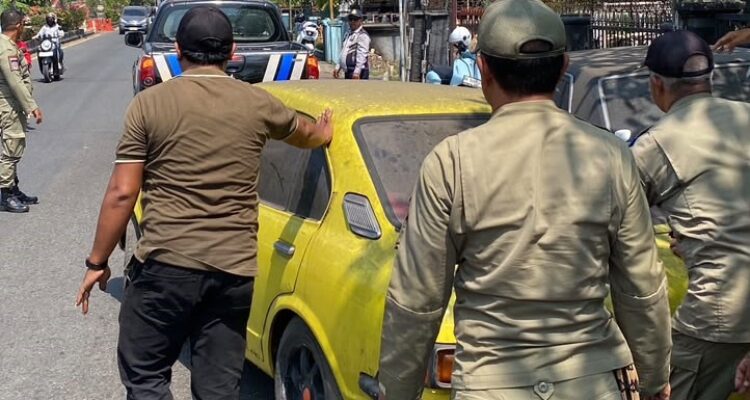 Ket poto: Petugas mendorong satu unit Toyota Corolla rusak saat penertiban kendaraan yang parkir di trotoar dan badan Jalan Udayana, Negara, Selasa (20/10/2026).